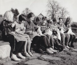 Bilde er tatt i februar 1961. Våren har alt gjort sitt inntog på Jæren. På bilde ser vi 4.kl. jenter ved Tasta Skole som koser seg med handarbeid under åpen himmel. Februarsola varmer godt, og det
grønskas og gror.
Fra venstre: Astri Aartun - Bente Hidle - Greta Aartun - Gunn Margrethe Haugsland - Judit Marie Hamre
Astrid Selvåg - Gerd Lillian Langerud - Wenche Torkildsen - Anne Grete Bjørnsen.